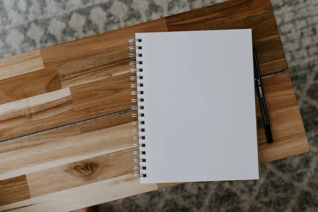 White spiral notebook on a wooden table for journaling about a birth chart reading